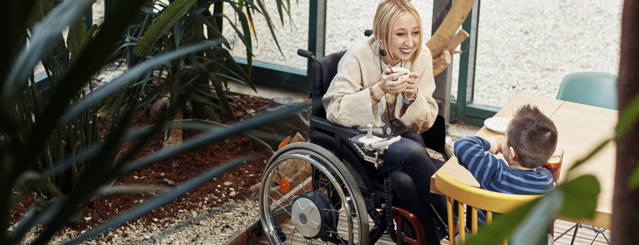 Picture of Eva in a wheelchair smiling to young boy